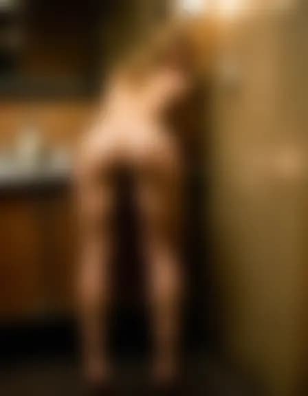 Olivia, bent over, in a dimly lit, cramped cafe restroom.